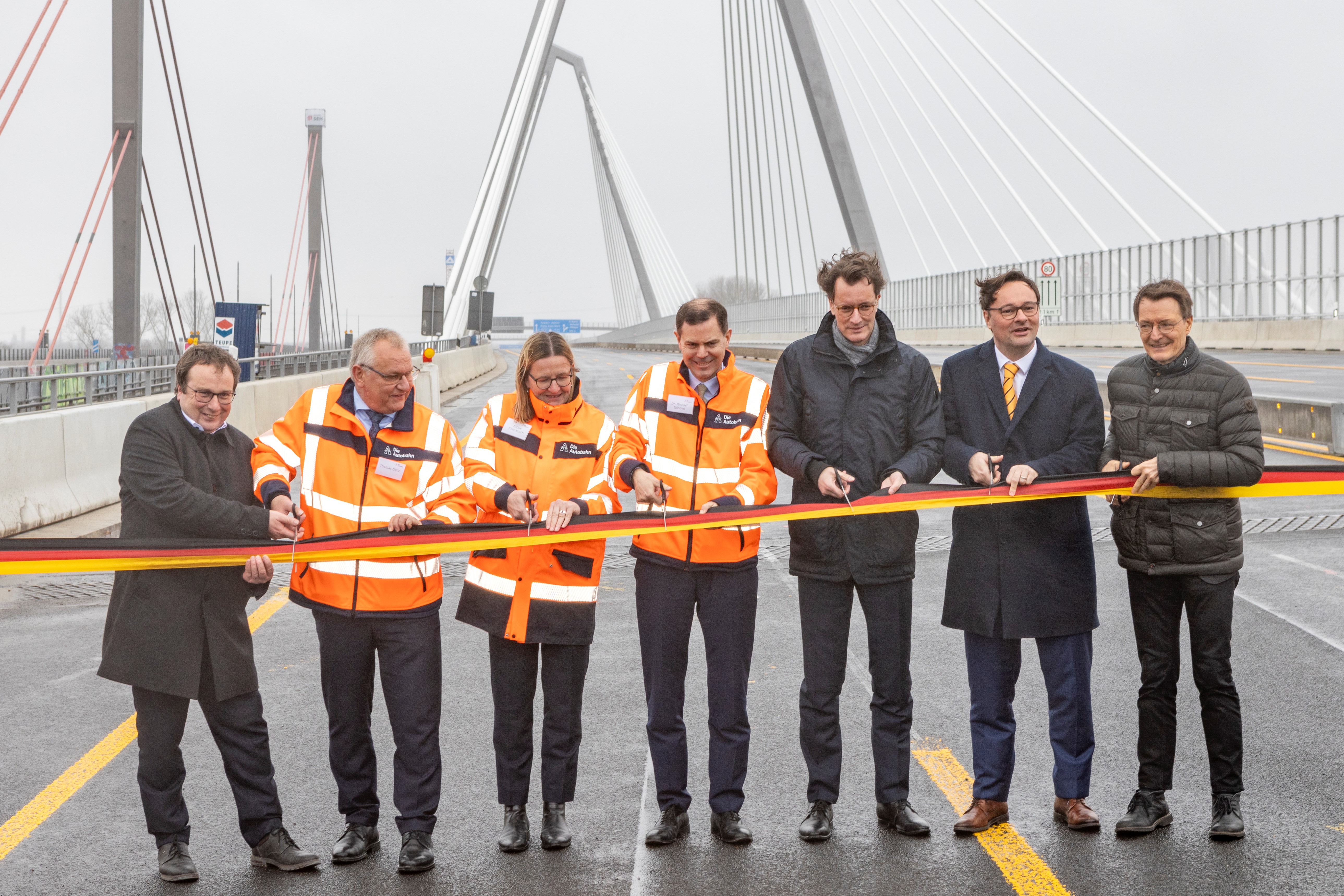 sieben Personen (Vertreter*innen der Autobahn GmbH und der Politik) durschneiden feierlich ein Band auf der neuen Rheinbrücke Leverkusen